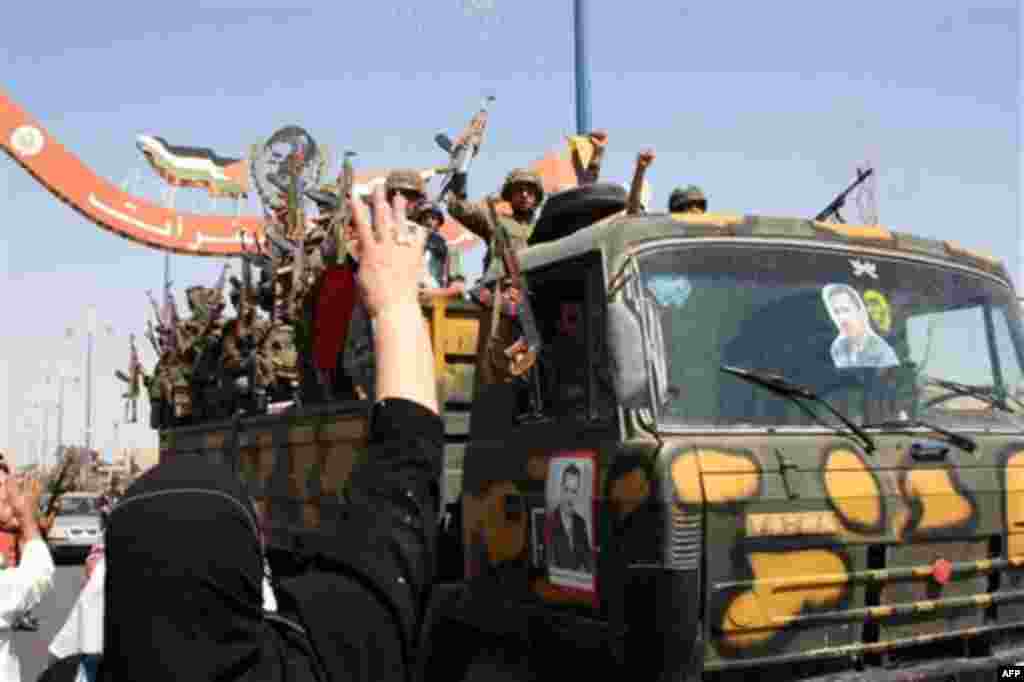In this photo taken on a government-organized tour, a Syrian woman throws rice at cheering Syrian soldiers as they leave the eastern city of Deir el-Zour, Syria, Tuesday, Aug. 16, 2011. State-run news agency SANA said army units began withdrawing from Dei