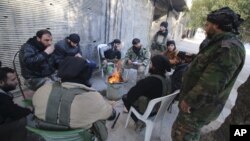 Rebel fighters of al-Jabha al-Shamiya (Levant Front) warm themselves around a fire near the justice palace in the old city of Aleppo, Syria, Jan. 28, 2016. 