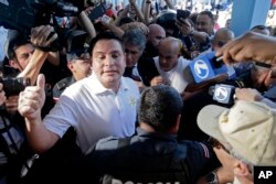 Presidential candidate Fabricio Alvarado, with the National Restoration party, gives a thumbs-up as he's surrounded by the press at a polling station during general elections in San Jose, Costa Rica, Feb. 4, 2018.