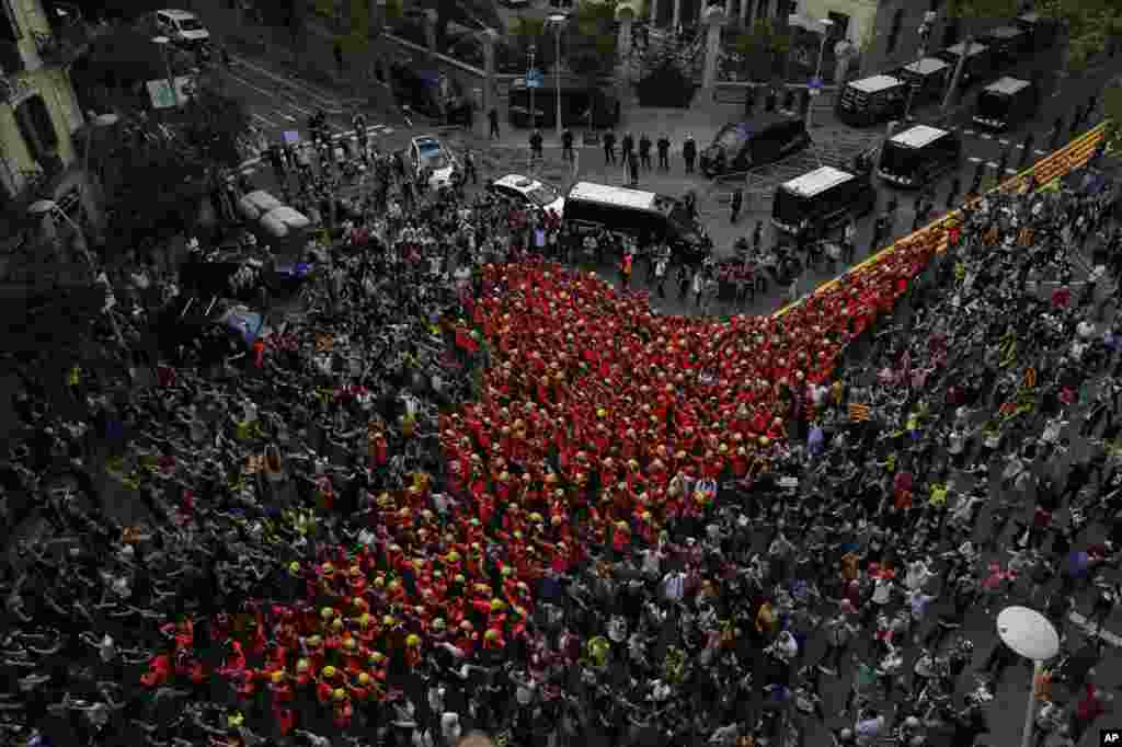 Firefighters join protesters outside the Spanish police headquaters during a one-day strike in Barcelona, Spain, Oct. 3, 2017. Labor unions and grassroots pro-independence groups are urging workers to hold partial or full-day strikes throughout Catalonia to protest alleged brutality by police during a referendum on the region&#39;s secession from Spain that left hundreds of people injured.