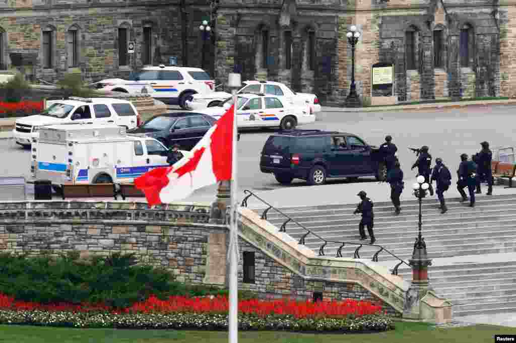 Armed RCMP officers approach Centre Block on Parliament Hill following a shooting incident in Ottawa, Canada, Oct. 22, 2014. A Canadian soldier was shot at the Canadian War Memorial and a shooter was seen running towards the nearby parliament buildings, where more shots were fired, according to media and eyewitness reports. 