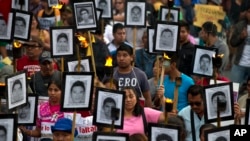 FILE - Family members and supporters of 43 missing college students from Guerrero state carry pictures of the students as they demand the case not be closed, in Mexico City, April 26, 2016. An international probe into the 2014 disappearance of the student was reportedly targeted with spying software sold to governments to fight criminals and terrorists.
