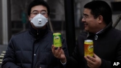Multimiliuner Tiongkok, Chen Guangbiao (kanan) memberikan udara bersih kalengan pada seorang pria yang memakai masker udara karena polusi yang parah di Beijing (30/1). (Reuters/Barry Huang)