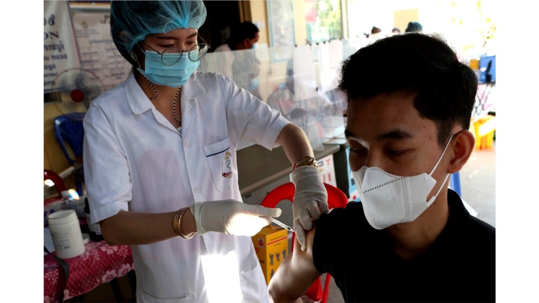 Seorang pria Kamboja (kanan), menerima suntikan dosis keempat vaksin COVID-19 Pfizer di pusat kesehatan Phnom Penh, Kamboja, Jumat, 14 Januari 2022.