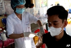 Seorang pria Kamboja (kanan), menerima suntikan dosis keempat vaksin COVID-19 Pfizer di pusat kesehatan Phnom Penh, Kamboja, Jumat, 14 Januari 2022.