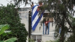 El actor, dramaturgo y líder del proyecto Archipiélago Yunior García, de 39 años, es visto detrás de una ventana de su casa mientras la gente cuelga una bandera cubana en la azotea, en La Habana, Cuba, el 14 de noviembre de 2021.