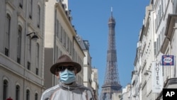 Un hombre usa una máscara para protegerse del coronavirus mientras camina por una calle cercana a la Torre Eiffel en París, el domingo 26 de abril de 2020.