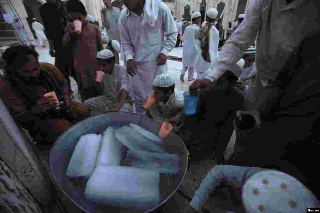 Men and boys drink water after breaking their fast, on the first day of Ramadan, at a mosque in Peshawar, June 29, 2014. 