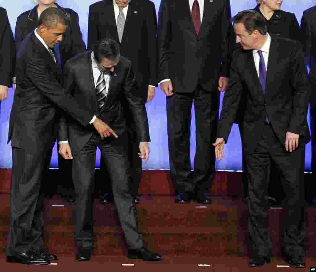 President Barack Obama and British Prime Minister David Cameron help Secretary General Anders Fogh Rasmussen find his toe marker.