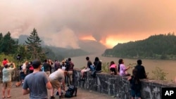 People at a viewpoint overlooking the Columbia River watching the Eagle Creek wildfire burning in the Columbia River Gorge east of Portland, Ore., Sept. 4, 2017.