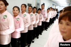 FILE - Graduates of Ayi University, a training program for domestic helpers, line up to meet potential employers in Beijing, China, Dec. 11, 2018.