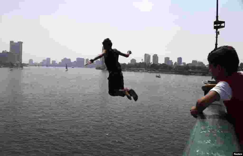 A boy watches another jump from a bridge to cool off in the river Nile during Eid al-Fitr in Cairo August 20, 2012. 