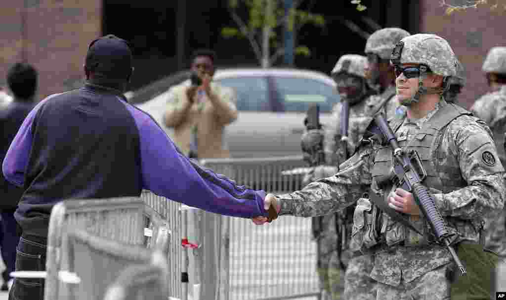 A man shakes hands with a National Guard soldier outside City Hall in Baltimore, Maryland. State&#39;s Attorney Marilyn J. Mosby announced criminal charges Friday, against all six officers suspended after Freddie Gray suffered a fatal spinal injury in police custody.