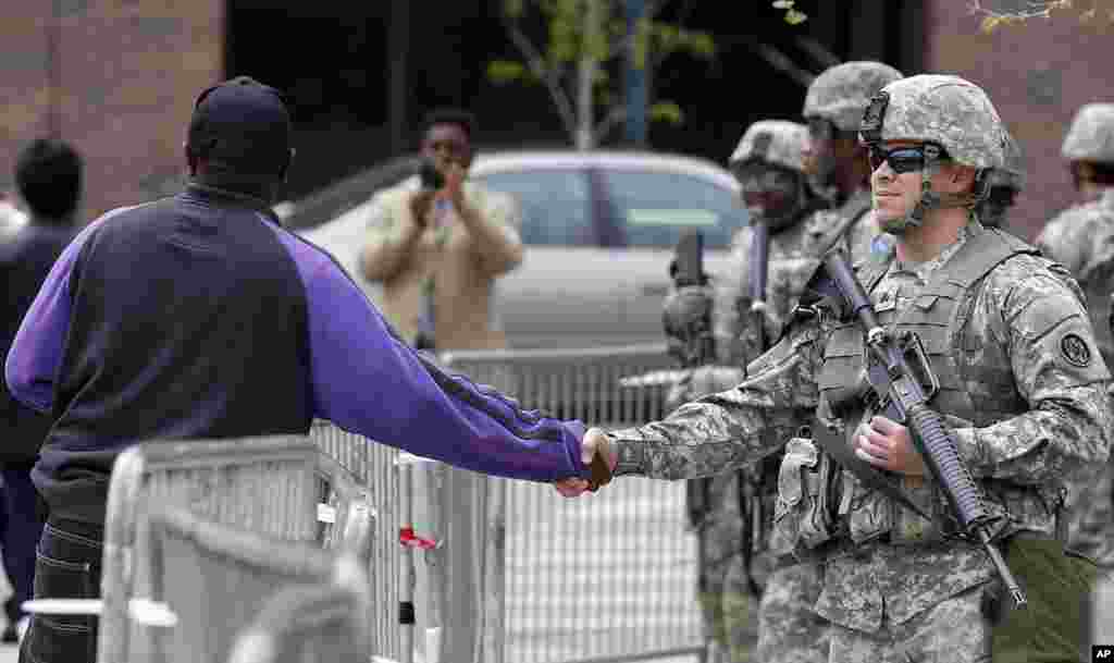 Seorang pria menjabat tangan seorang tentara di Balai Kota di Baltimore, Maryland. Jaksa negara bagian Marilyn J. Mosby mengumumkan tuntutan-tuntutan kriminal yang akan diajukan kepada enam polisi yang diskors setelah Freddie Gray menderita cidera tulang belakang yang fatal saat berada dalam tahanan polisi.