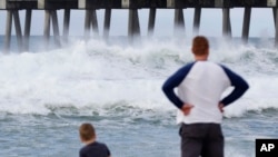 Otac i sin posmatraju talase kako se razbijaju o obalu dok podtropska oluja nadolazi, 28. maja 2018, u Pensakoli, Florida.