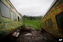 FILE - People look at derailed coaches of the Duronto Express in Asangaon, some 70 kilometers from Mumbai, India, Aug. 29, 2017.