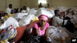 Election volunteers sit on bags containing ballots as they wait for tally sheets to be computed at the Fikin compilation center in Kinshasa, Democratic Republic of Congo, Thursday, Dec. 1, 2011.