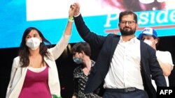 Chilean president-elect Gabriel Boric (R) and his chief of campaign Izkia Siches wave at supporters following the official results of the runoff presidential election, in Santiago, on December 19, 2021. (Photo by MARTIN BERNETTI / AFP)
