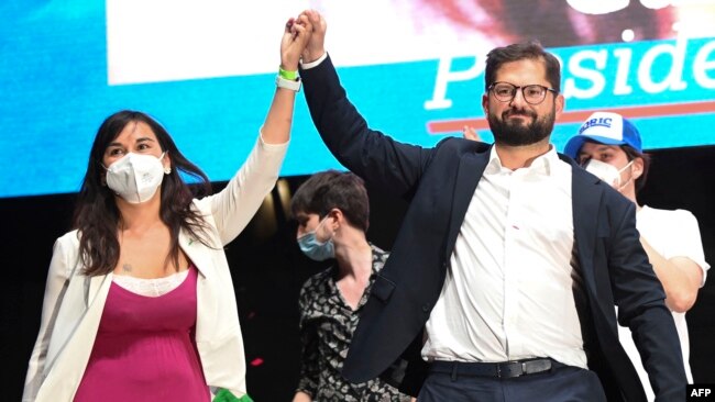 Chilean president-elect Gabriel Boric (R) and his chief of campaign Izkia Siches wave at supporters following the official results of the runoff presidential election, in Santiago, on December 19, 2021. (Photo by MARTIN BERNETTI / AFP)