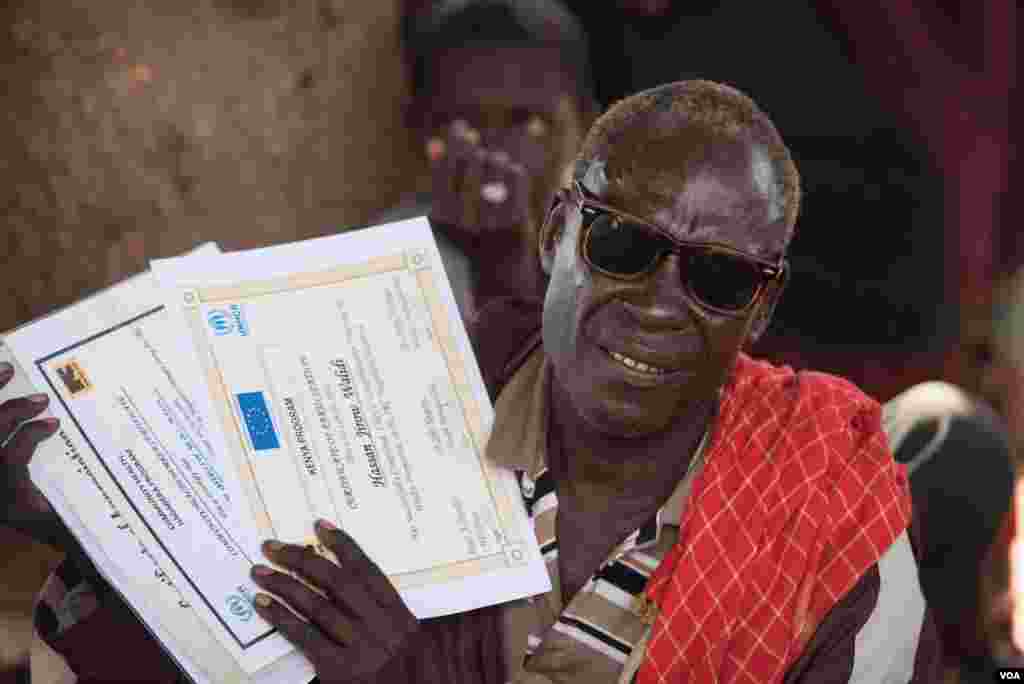 A refugee returned to Kismayo in Somalia holds up documents from his stay in Kenya's Dadaab camp on September 26, 2016. (J. Patinkin/VOA)