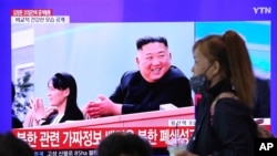 5月2日，首爾火車站以女子走過一電視屏幕，上面顯示北韓領導人金正恩與其妹妹金與正在一起參加一化肥廠完工儀式。