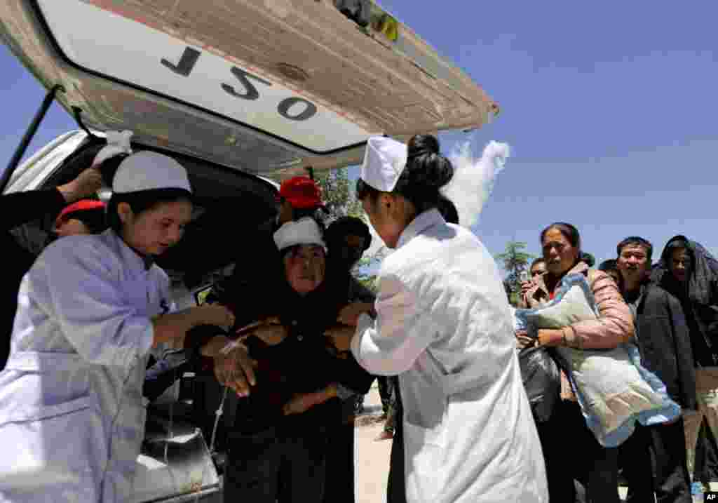 Seorang perempuan korban terluka dalam gempa ditolong oleh pekerja medis di daerah Minxian, provinsi Gansu, China (22/7).