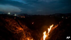 Flames rise out of the fissures on the ground above coal mines in the village of Liloripathra near Dhanbad, an eastern Indian city in Jharkhand state, Sept. 23, 2021. (AP Photo/Altaf Qadri)