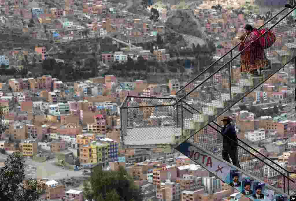 A man and a woman walk down the stairs of an overpass decorated with posters of Bolivia's President Evo Morales in La Paz, Oct. 9, 2014. Bolivia will hold general elections on Sunday. 