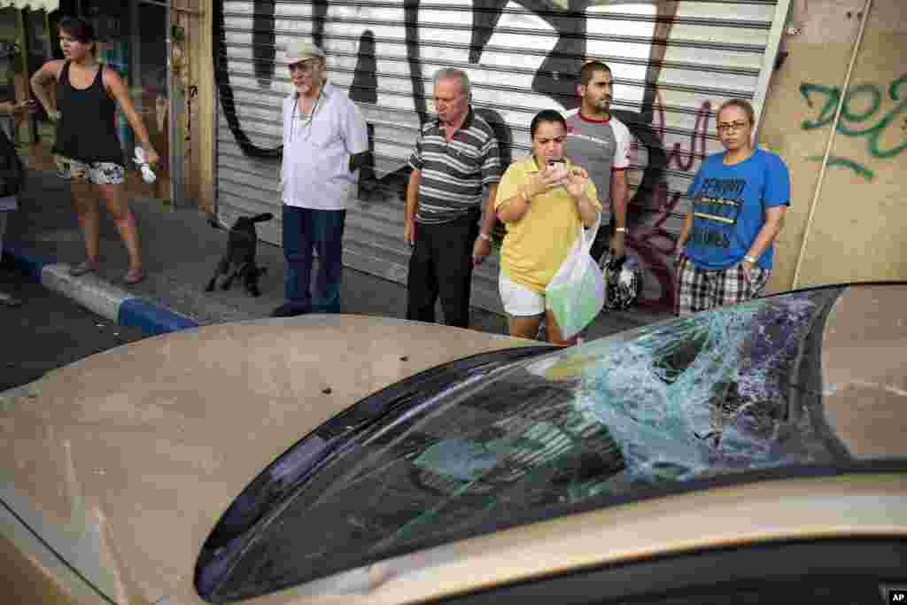 Israelis looks at a car damaged by remnants of a long-range rocket fired by Palestinians militants from Gaza after it was shot down by Israel’s "Iron Dome," in Tel Aviv, July 10, 2014. 