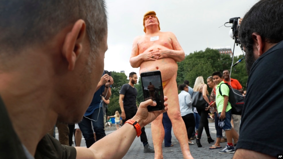 People take photos of a statue of a naked Republican presidential nominee Donald Trump in New York's Union Square, Aug. 18, 2016. City parks workers later removed the statue.