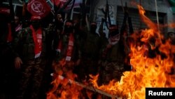 Palestinian militants of PFLP burn representations of an Israeli flag and a U.S. flag during a protest..
