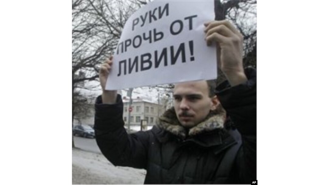 An activist of an anti-Kremlin opposition group, The Left Front, holds a poster reading 'Hands off Libya' during his picket at the NATO representative office in Moscow, Russia, March 19, 2011