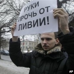 An activist of an anti-Kremlin opposition group, The Left Front, holds a poster reading 'Hands off Libya' during his picket at the NATO representative office in Moscow, Russia, March 19, 2011