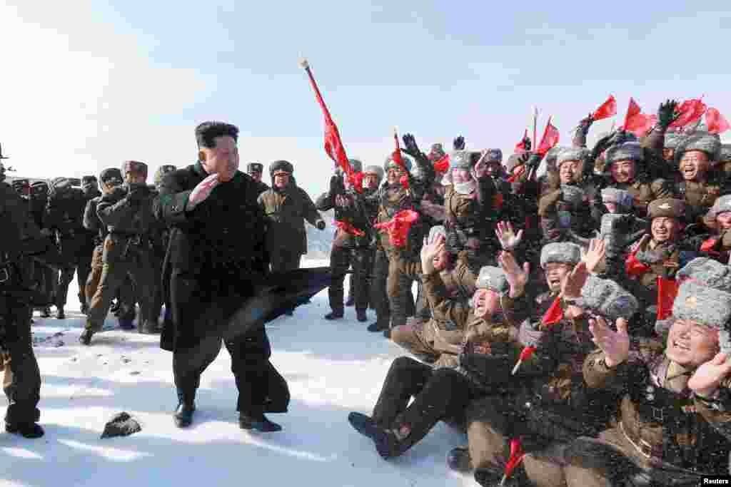 Pemimpin Korea Utara Kim Jong Un menyapa pilot tentara Korea dalam kunjungannya ke puncak gunung Paektu di foto yang disebarkan oleh Badan Berita Sentral Korea Utara (KNCA).
