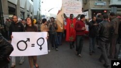 FILE - A woman activist carries a sign promoting gender equality at a rally in Rabat, Morocco.