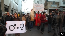 FILE - A woman activist carries a sign promoting gender equality at a rally in Rabat, Morocco.