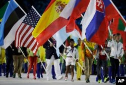 FILE - Simone Biles carries the flag of the United States during the closing ceremony in the Maracana stadium at the 2016 Summer Olympics in Rio de Janeiro, Brazil, Aug. 21, 2016.