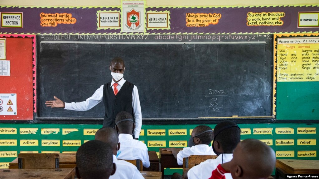 A teacher welcomes back students during a classroom lesson on day one of re-opening schools in Kampala, Uganda, Jan. 10, 2022.