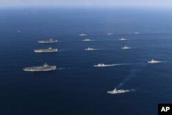 In this Nov. 12, 2017 photo provided by South Korea Defense Ministry, three U.S. aircraft carriers USS Nimitz, left top, USS Ronald Reagan, left center, and USS Theodore Roosevelt, left bottom, participate with other U.S. and South Korean navy ships.