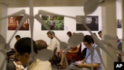 FILE - Portraits of farmers whose lands were confiscated hang on display while journalists attend a press briefing on a release of a project entitled "Nothing for Our Land," July 17, 2018, in Yangon, Myanmar.