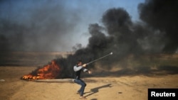 Un Palestinien jette des pierres contre l'armée israélienne, dans la bande de Gaza, le 1er avril 2018