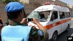 A UN observer photographs an ambulance that was destroyed after a car bomb exploded near the shrine of Sayyida Zeinab, in a suburb of Damascus, Syria, June 14, 2012.