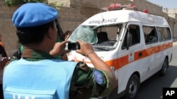 一位联合国观察员6月14日在大马士革郊外给一辆因炸弹袭击受损的救护车拍照