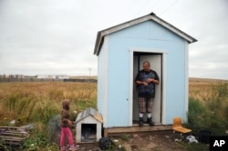 In this Wednesday, Sept. 30, 2015, photo, Raymond Eagle Hawk, right, stands in the doorway of his home that he shares with his daughter, Kimimila Eagle Hawk, left, and his girlfriend in Wounded Knee, S.D., on the Pine Ridge Indian Reservation.