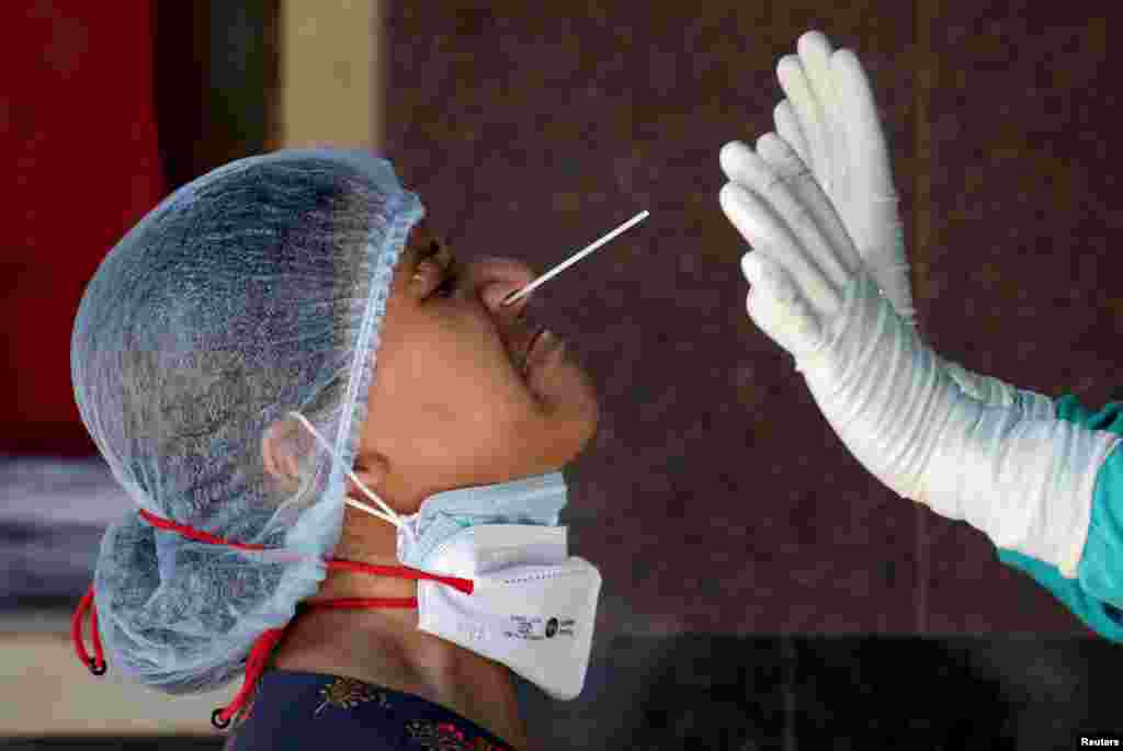 A woman reacts as a healthcare worker takes a nasal swab sample for a COVID-19 test at a government-run hospital in Kolkata, India.
