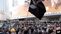 香港抗议者2019年6月21日在香港警察总部外挥舞染成黑色的香港特区旗帜抗议警方暴力。