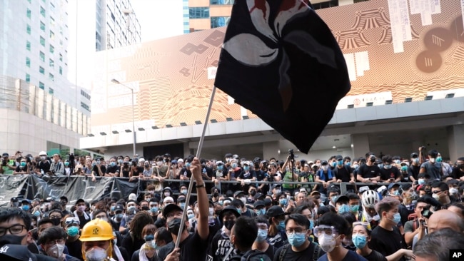 香港抗议者2019年6月21日在香港警察总部外挥舞染成黑色的香港特区旗帜抗议警方暴力。