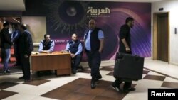 Watched by security personnel, a man carrying a suitcase leaves the shuttered offices of Saudi-owned TV news channel Al Arabiya in Beirut, Lebanaon, April 1, 2016.