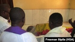 Des responsables catholiques à la morgue devant le corps de l'abbé Albert Tongomalé Baba tué dans l'attaque de l'Eglise FAtima, à Bangui, 1er mai 2018. (VOA/Freeman Sipila)