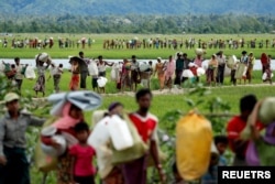 FILE - Rohingya refugees, who crossed the border from Myanmar two days before, walk after they received permission from the Bangladeshi army to continue on to the refugee camps, in Palang Khali, near Cox's Bazar, Bangladesh, Oct. 19, 2017.